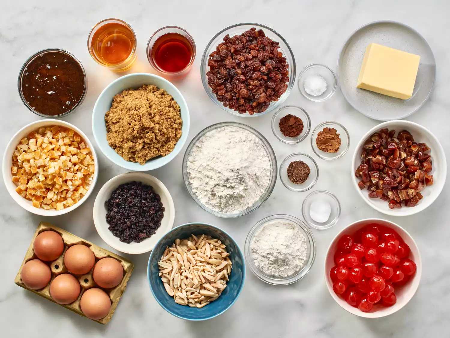 کاسه ها و بشقاب های مختلف پر از مواد لازم برای طرز تهیه کیک کریسمس. 